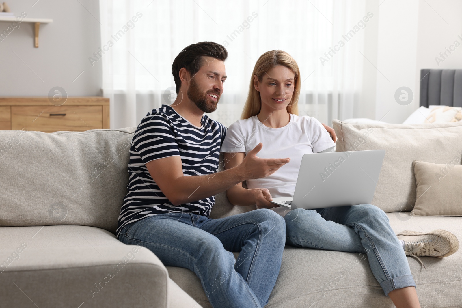 Photo of Happy couple with laptop on sofa at home