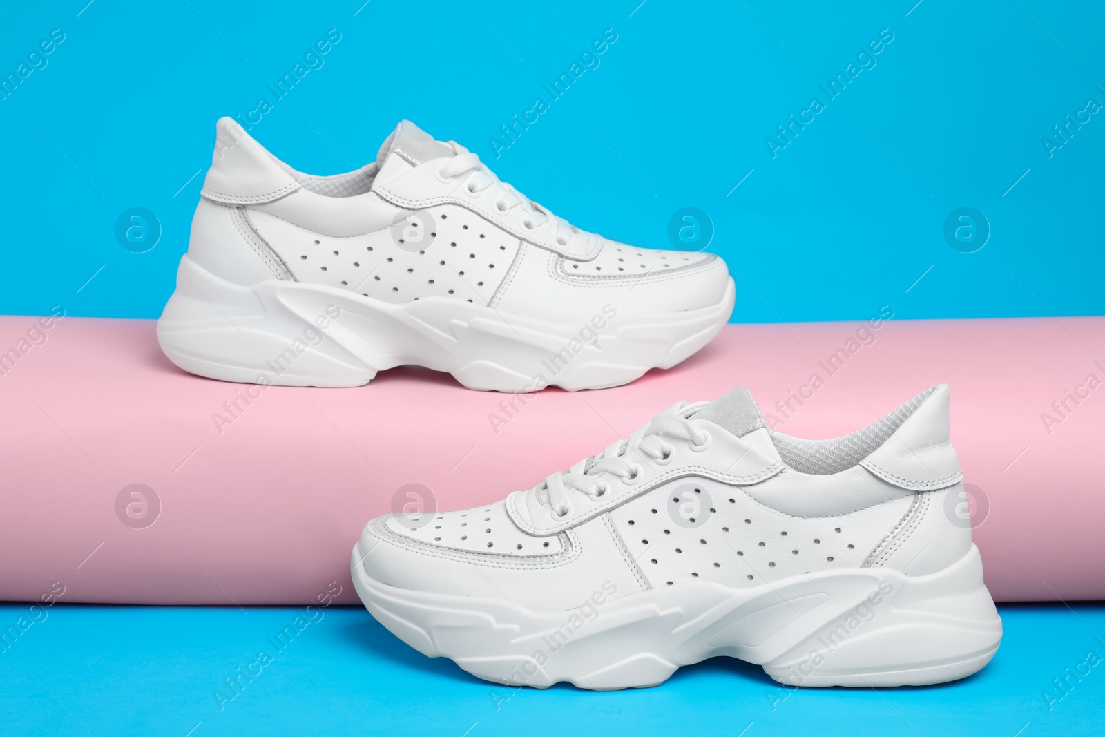 Photo of Stylish white sneakers on light blue background