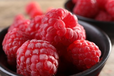 Photo of Tasty ripe raspberries in black bowl, closeup
