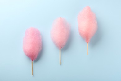 Photo of Sweet pink cotton candies on light blue background, flat lay