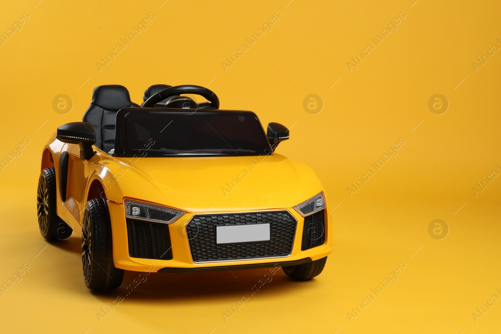 Photo of Child's electric toy car on yellow background. Space for text