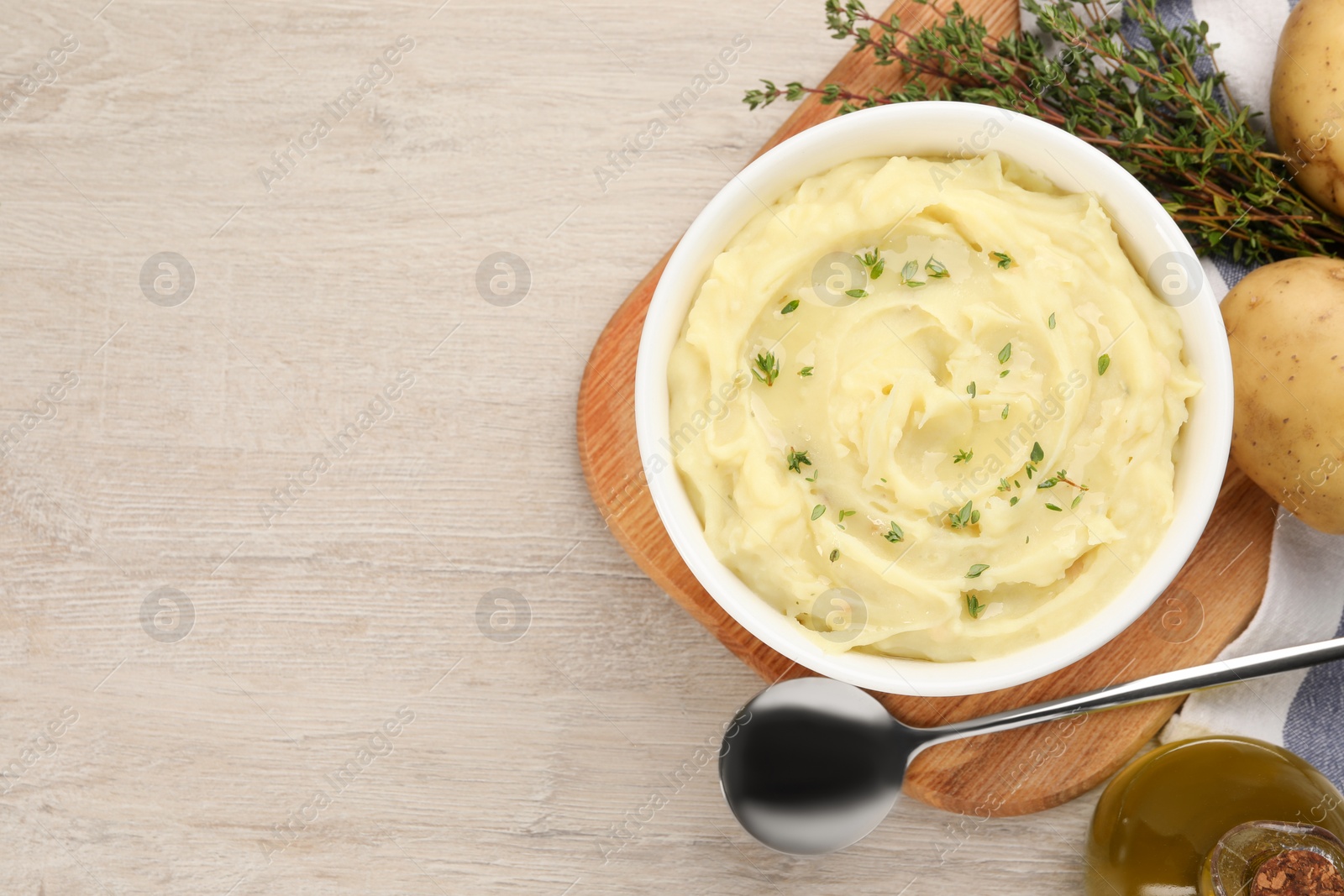Photo of Bowl of tasty mashed potato with rosemary and olive oil on beige wooden table, flat lay. Space for text