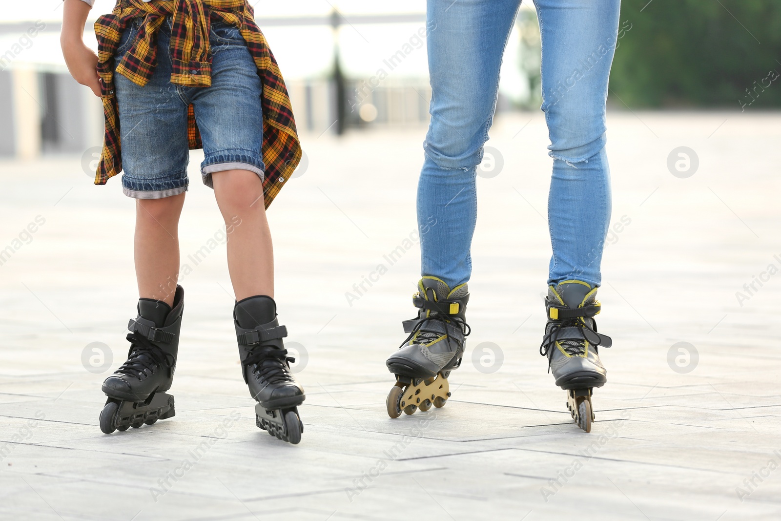 Photo of Father and son roller skating on city street, closeup of legs