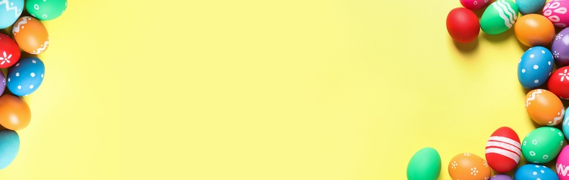 Image of Colorful Easter eggs and space for text on yellow background, flat lay. Horizontal banner design