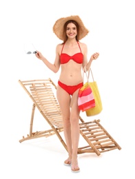 Young woman with beach accessories near sun lounger against white background