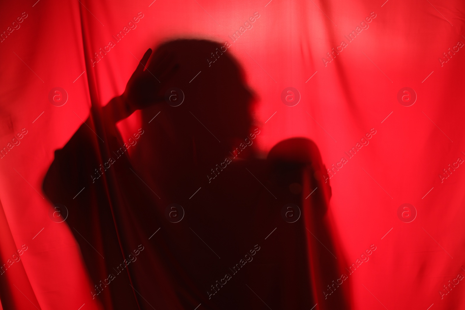 Photo of Silhouette of creepy ghost with skull behind red cloth, space for text