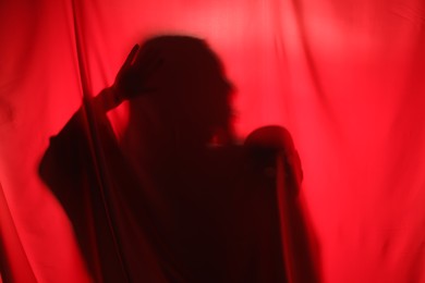 Silhouette of creepy ghost with skull behind red cloth, space for text