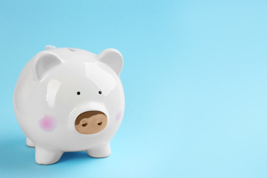 Photo of White piggy bank on light blue background. Space for text