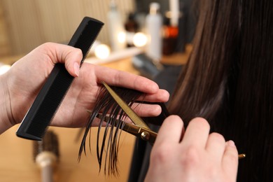 Photo of Hairdresser cutting client's hair with scissors in salon, closeup