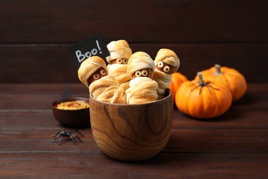 Photo of Spooky sausage mummies for Halloween party served on wooden table