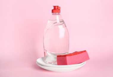 Photo of Detergent, plates and sponge on pink background. Clean dishes