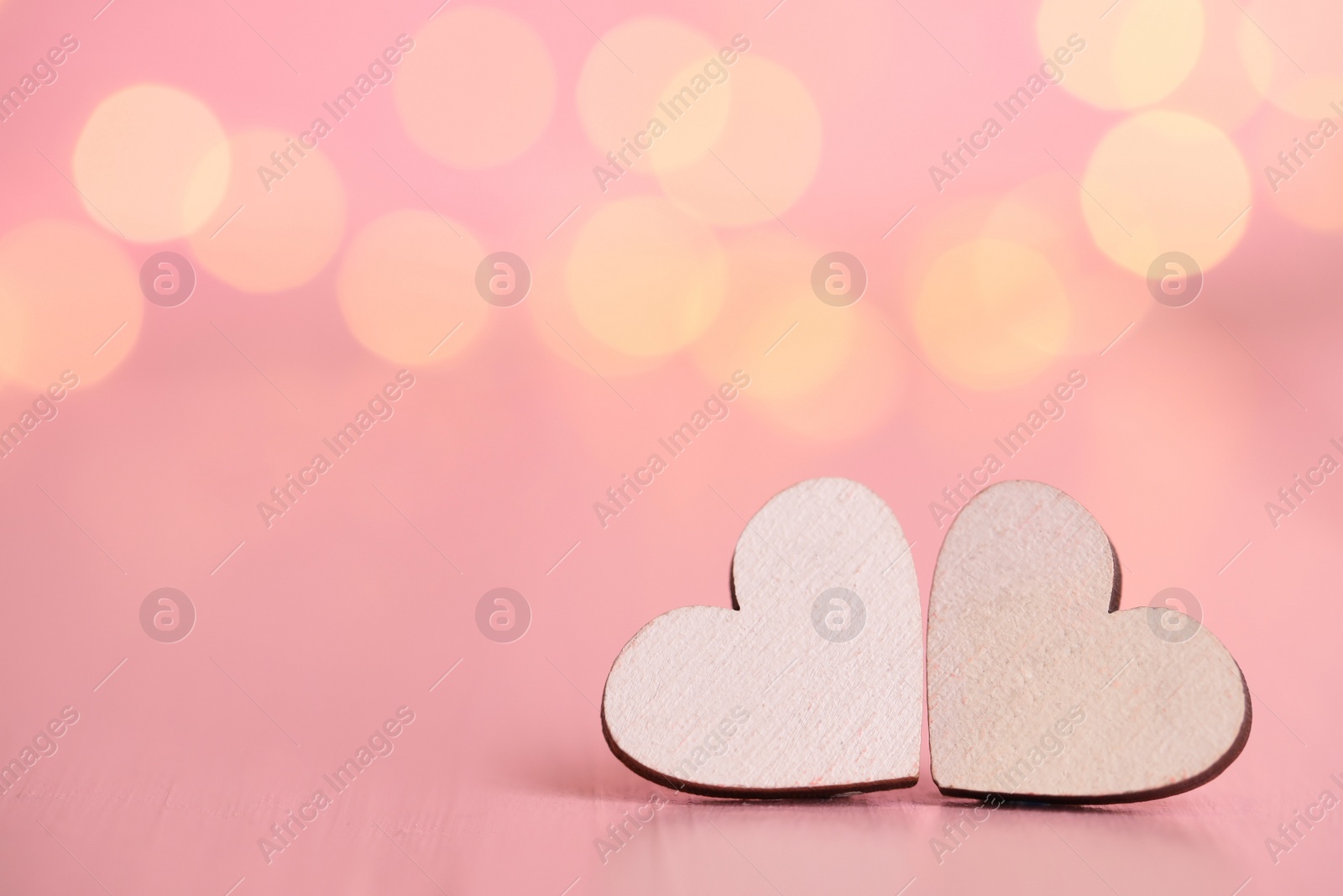 Photo of White hearts on wooden table against festive lights, space for text. St. Valentine's day