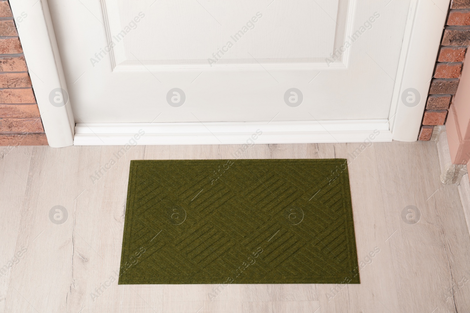 Photo of Dark olive door mat on wooden floor in hall, above view