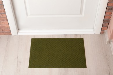 Dark olive door mat on wooden floor in hall, above view