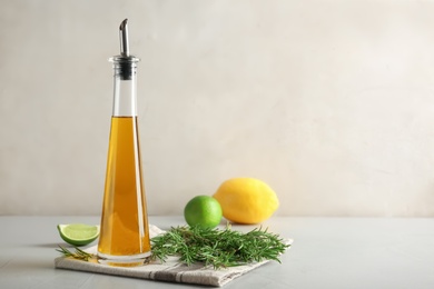 Photo of Bottle with fresh rosemary oil on table