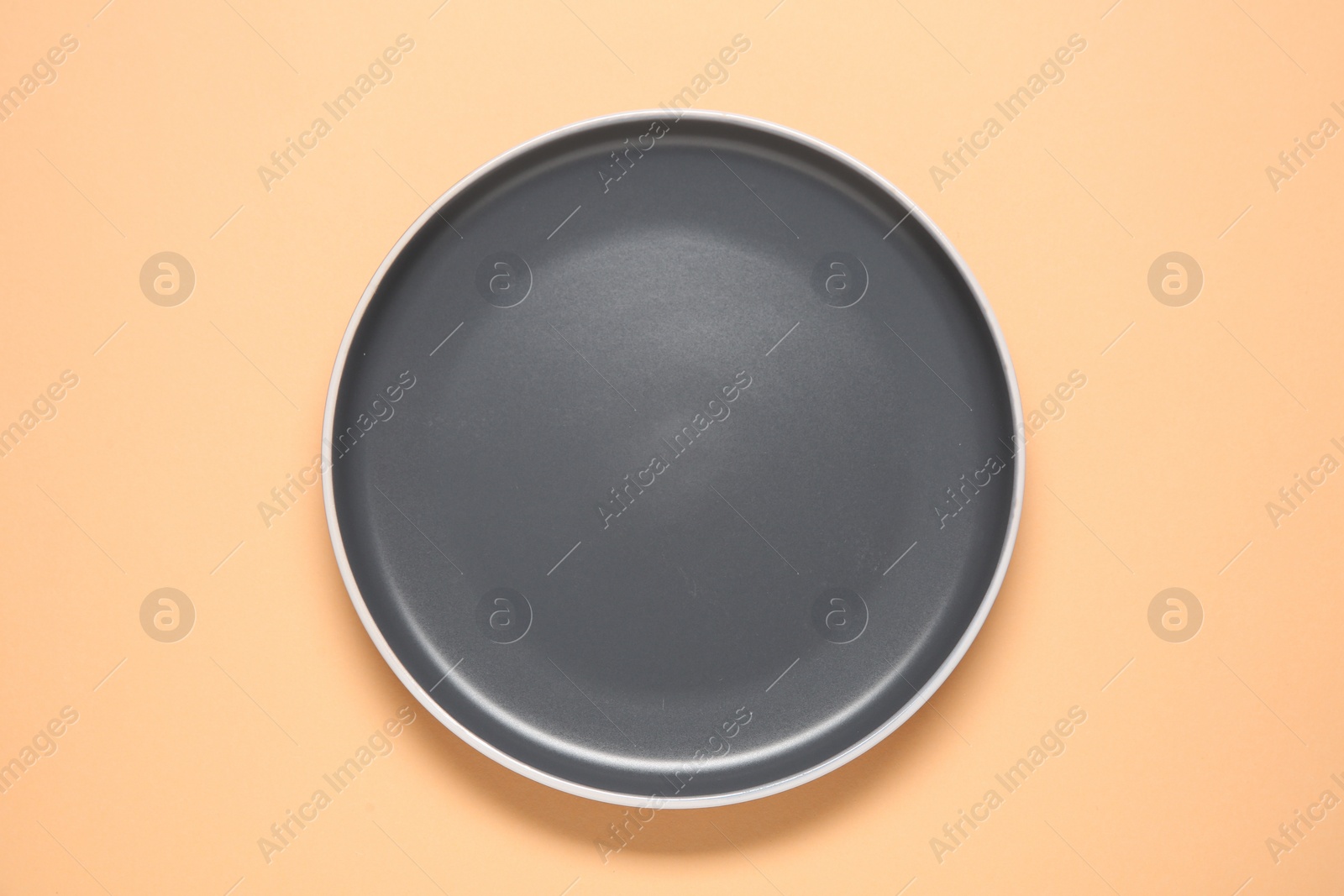 Photo of One grey ceramic plate on beige background, top view