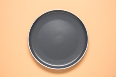 Photo of One grey ceramic plate on beige background, top view