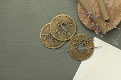 Photo of Acupuncture needles, moxa sticks and antique Chinese coins on grey wooden table, flat lay. Space for text