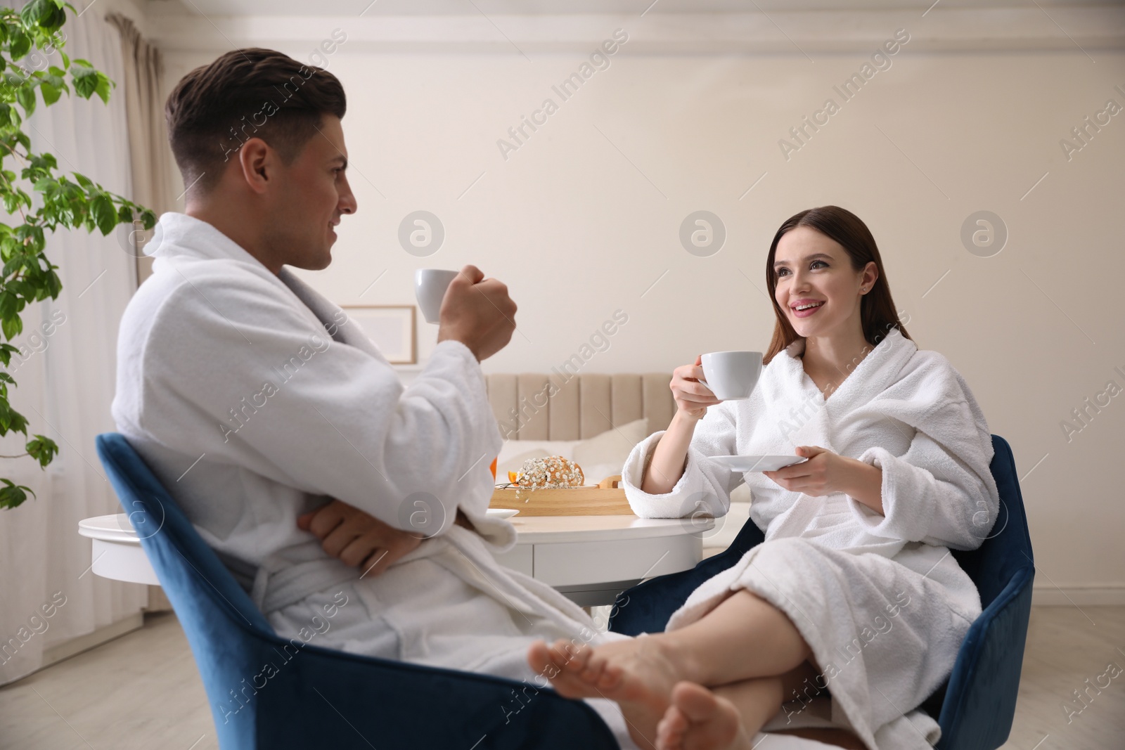 Photo of Happy couple in bathrobes having breakfast at home