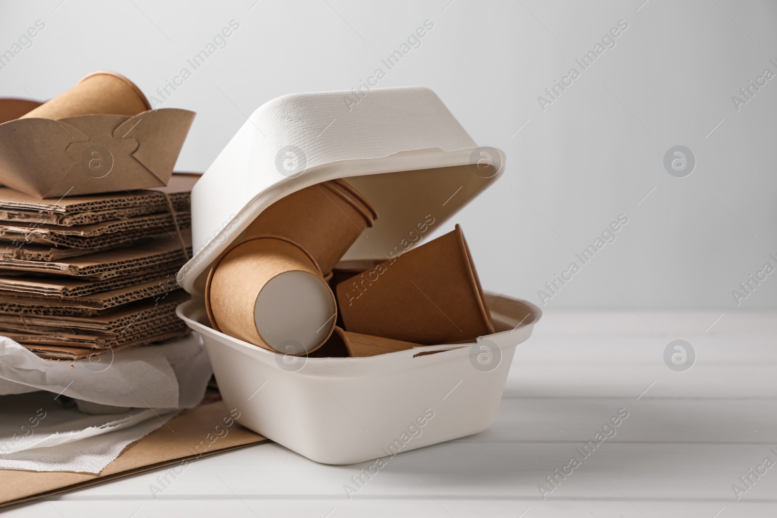 Photo of Heap of waste paper on white wooden table, space for text