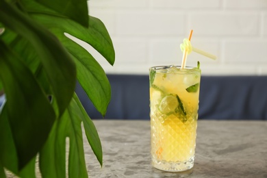 Glass of iced lemonade on table indoors