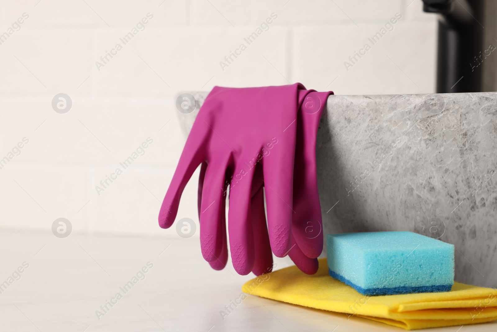 Photo of Sponge, rag and rubber gloves near sink in bathroom. Space for text