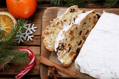 Photo of Traditional Christmas Stollen with icing sugar on wooden table, flat lay