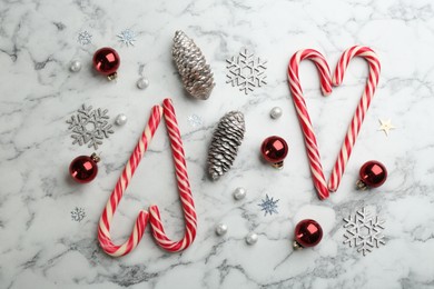 Flat lay composition with candy canes and Christmas decor on white marble table