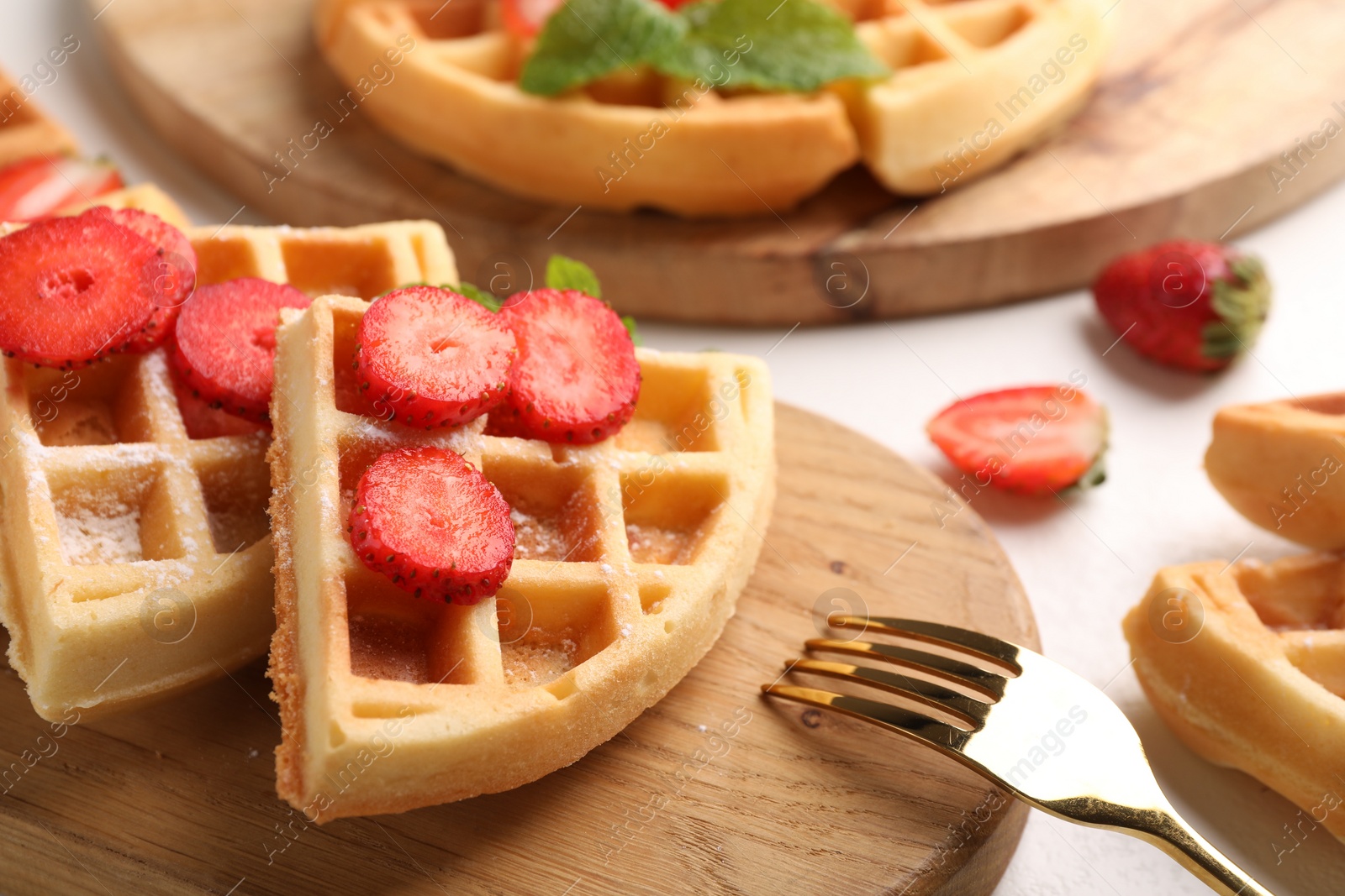 Photo of Tasty Belgian waffles with strawberries, mint and fork on white table, closeup