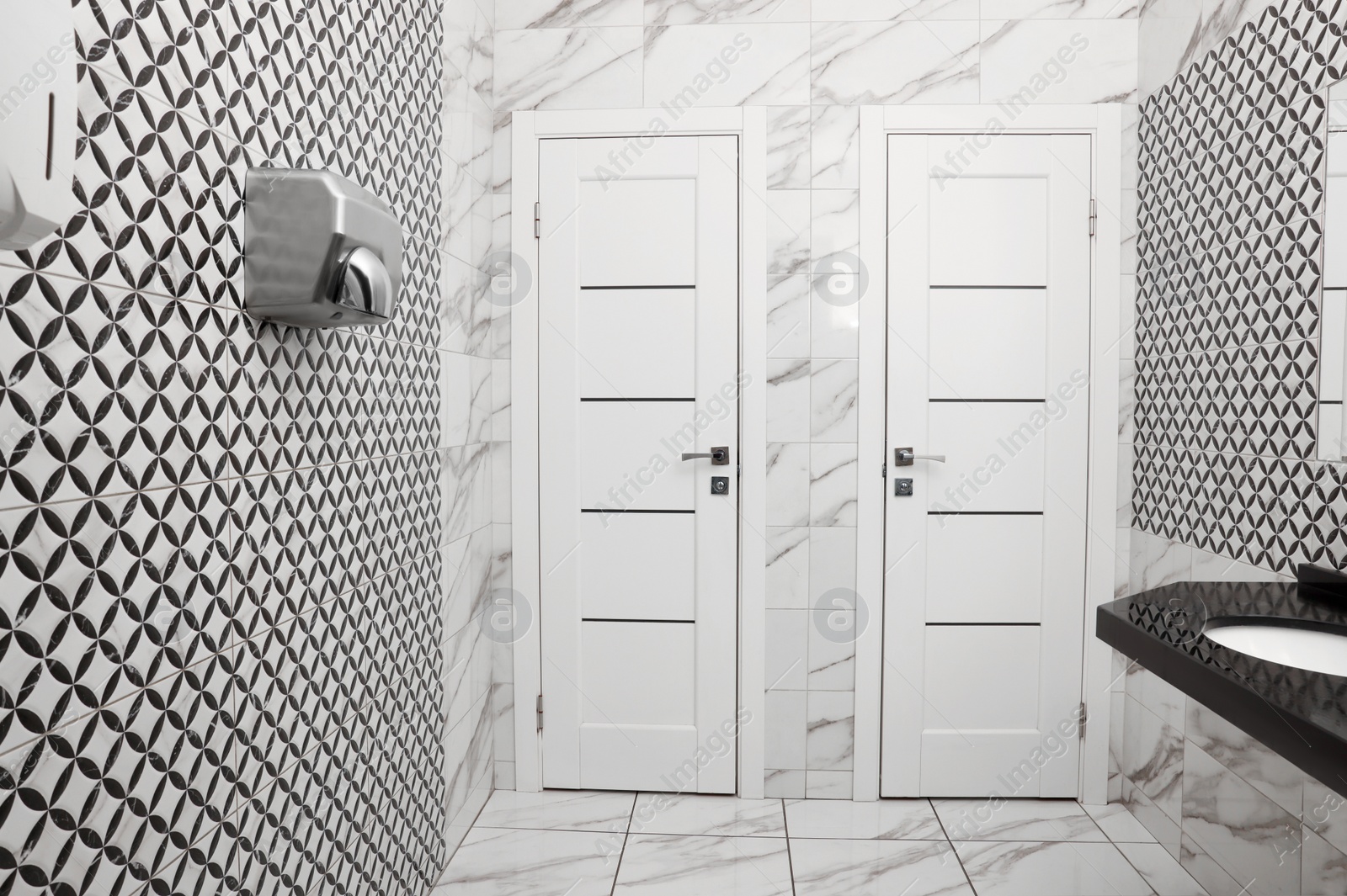 Photo of Public toilet interior with stylish white tiles