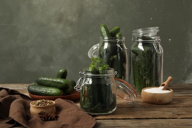 Photo of Pickling jars with fresh ripe cucumbers and spices on wooden table