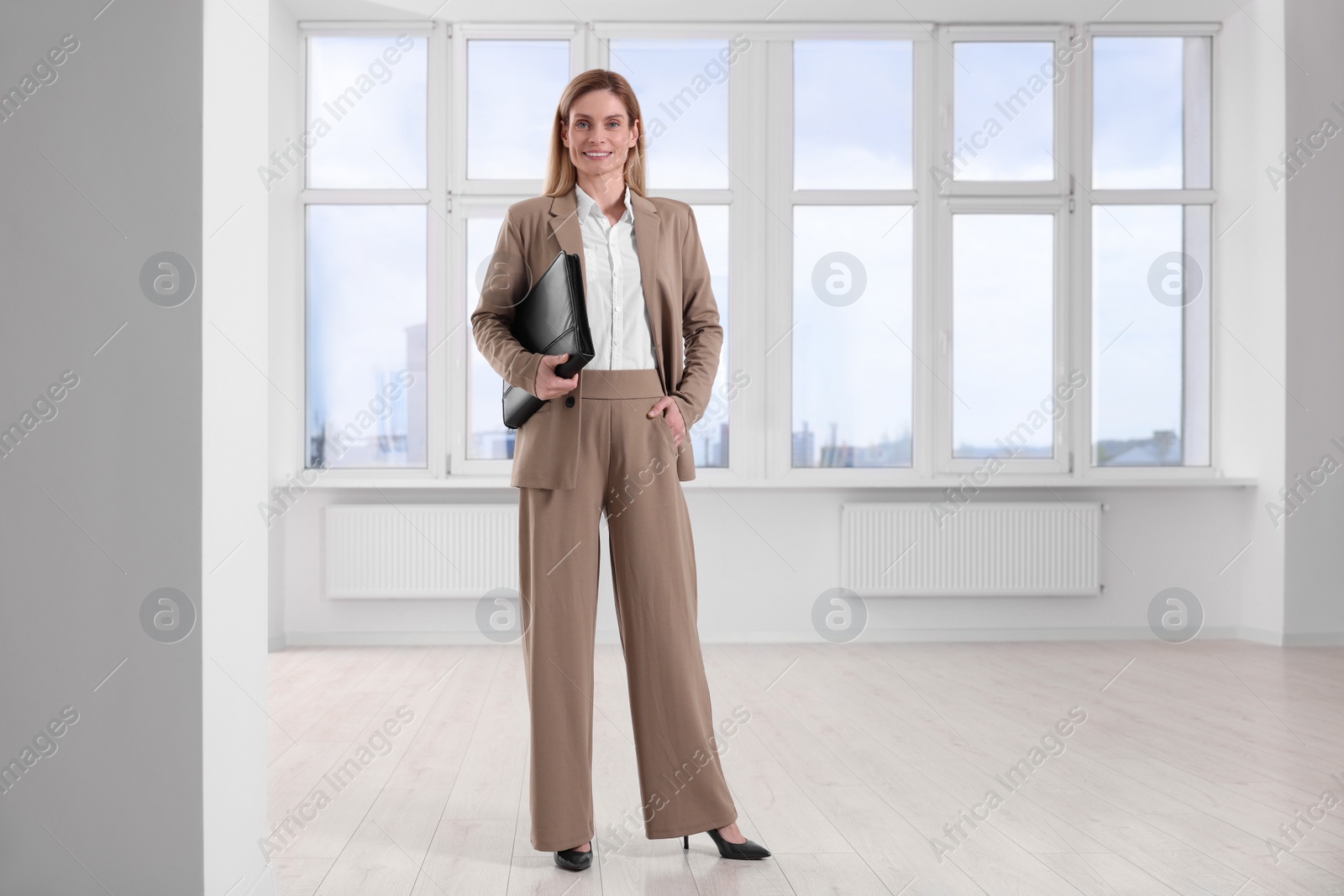 Photo of Happy real estate agent with leather portfolio in new apartment