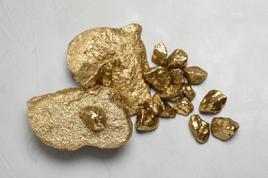 Pile of gold nuggets on light grey table, flat lay