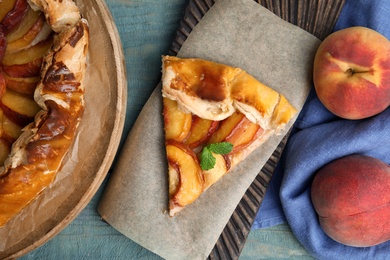 Photo of Delicious fresh peach pie on blue wooden table, flat lay