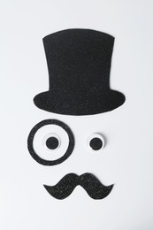 Photo of Man's face made of fake mustache, hat, eyes and monocle on white background, top view