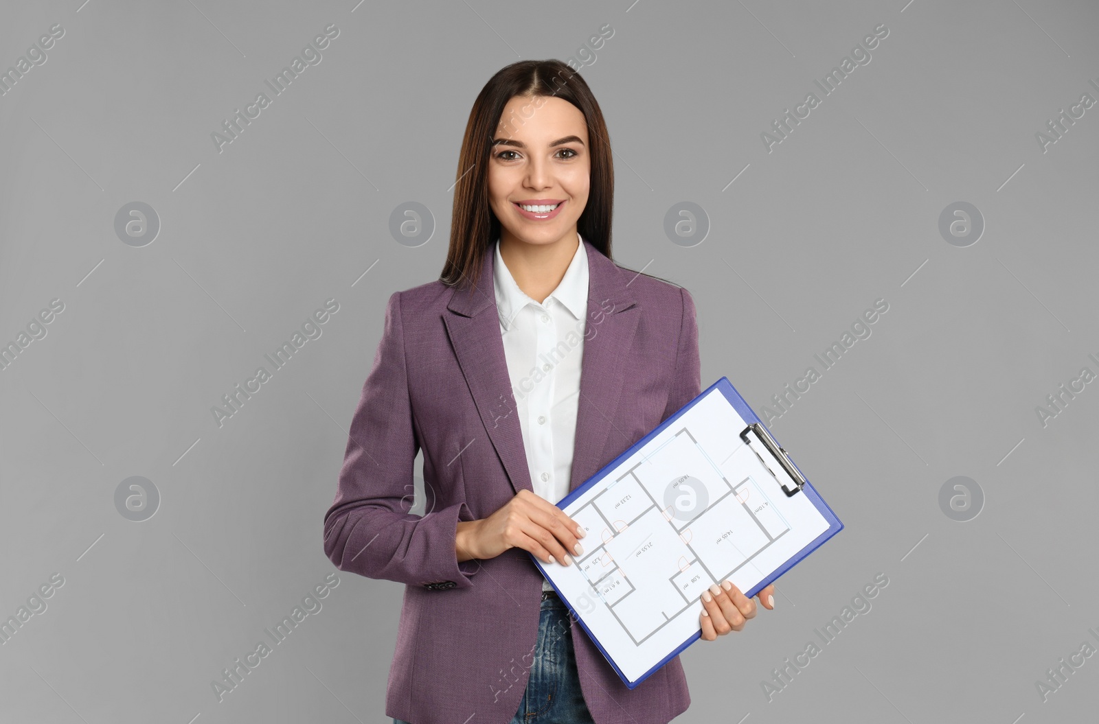 Photo of Female real estate agent with clipboard on grey background
