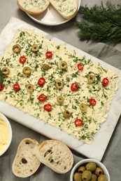 Photo of Fresh butter board with cut olives, dill and bread on grey table, flat lay