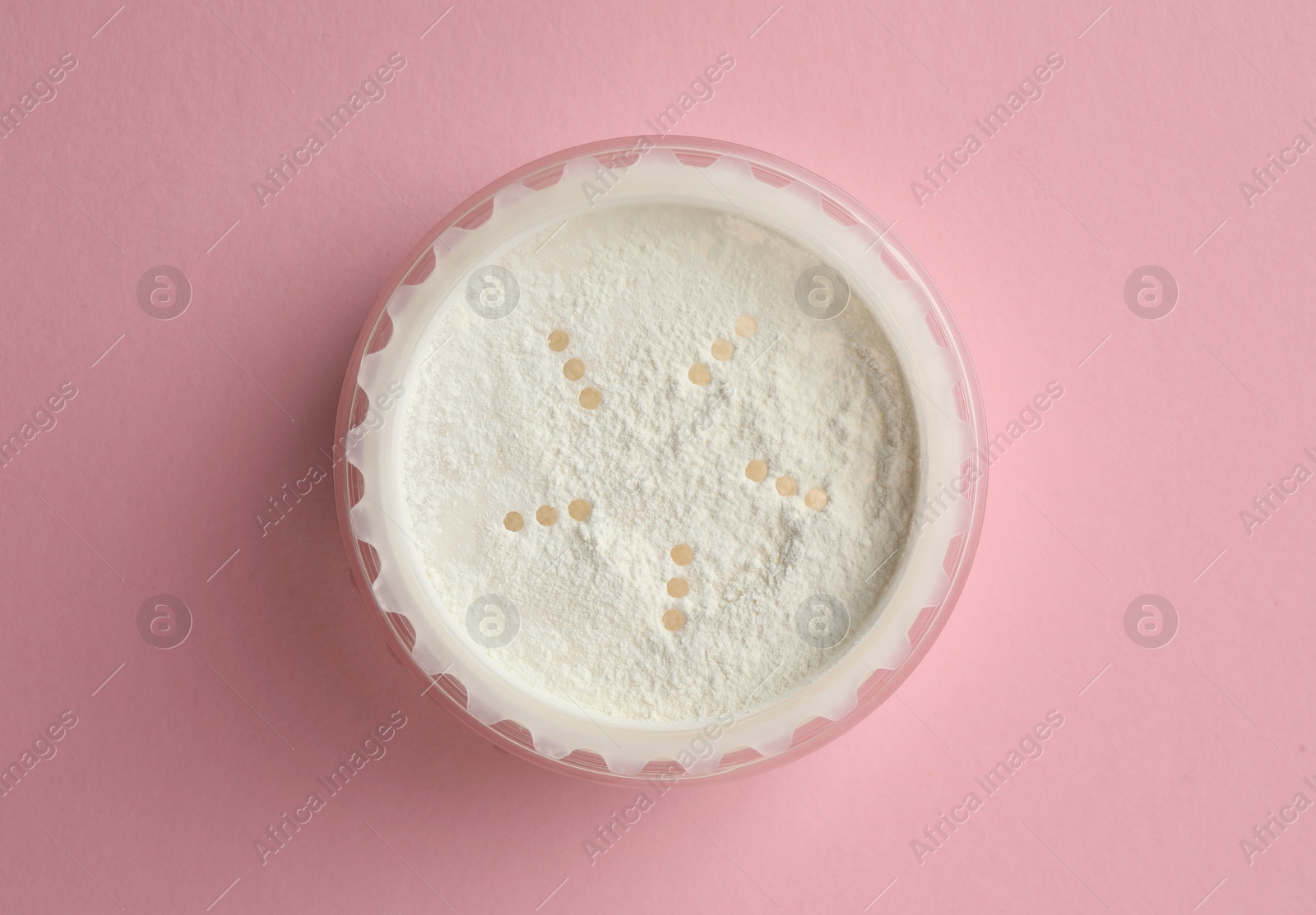 Photo of Rice loose face powder on pink background, top view. Makeup product