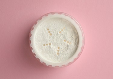 Rice loose face powder on pink background, top view. Makeup product