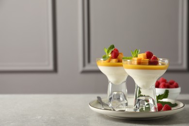 Delicious panna cotta with mango and raspberries on grey table. Space for text