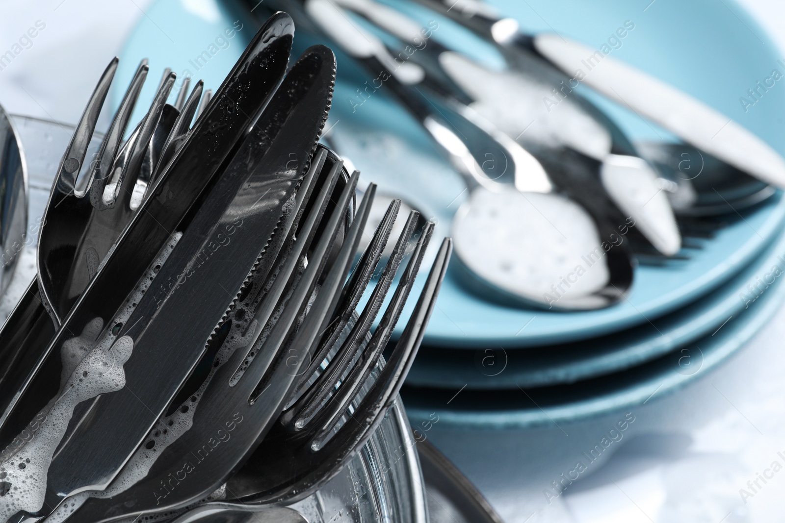 Photo of Glass bowl with silverware in foam, closeup