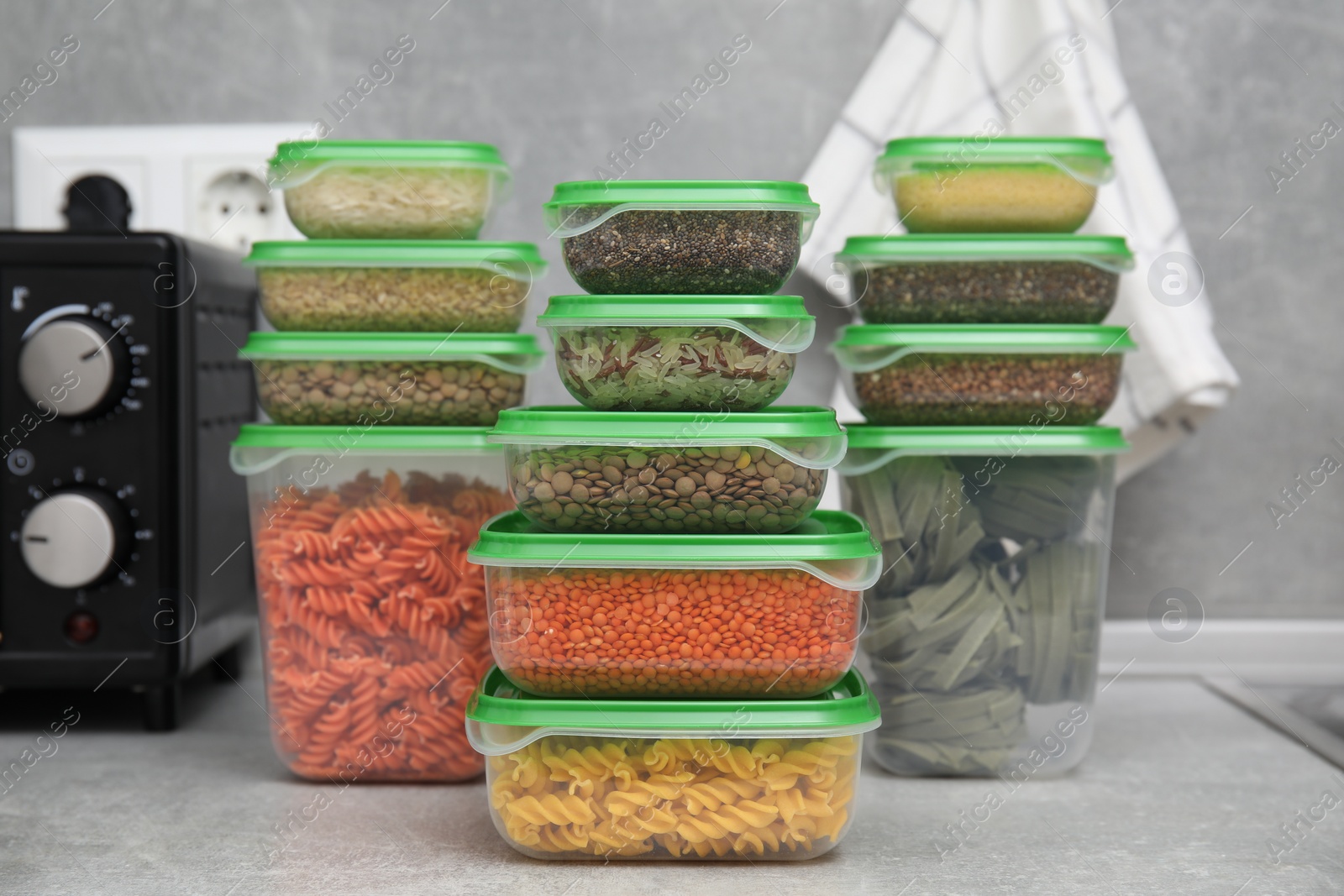 Photo of Plastic containers filled with food products on grey table in kitchen