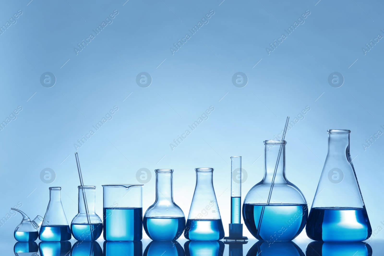 Photo of Laboratory glassware with liquid on table against color background. Chemical analysis