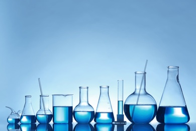 Laboratory glassware with liquid on table against color background. Chemical analysis