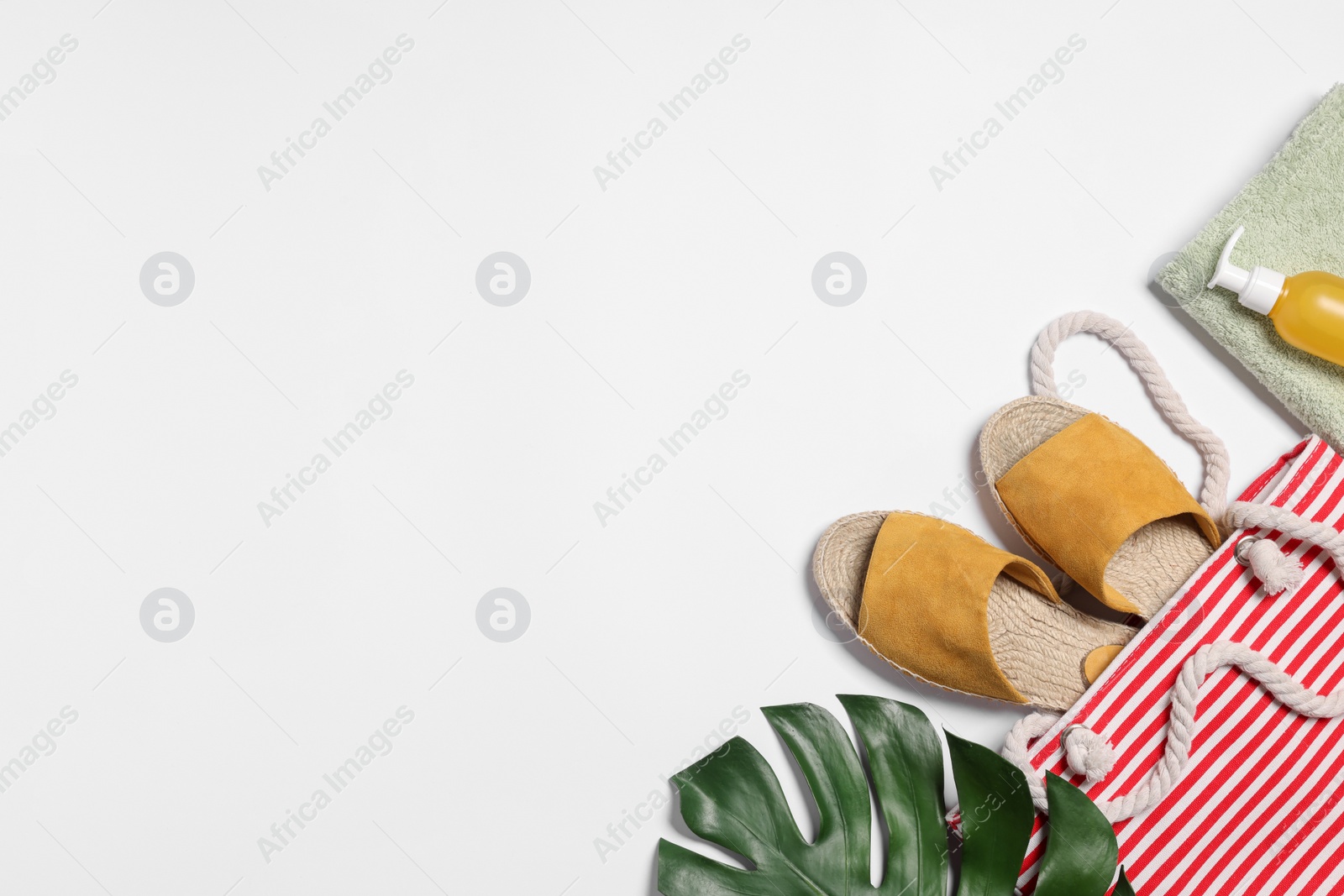 Photo of Flat lay composition with bag, green leaf and other beach accessories on white background. Space for text