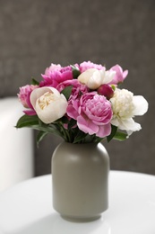 Photo of Vase with bouquet of beautiful peonies on table in room