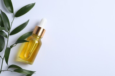 Bottle of cosmetic oil and leaves on white background, flat lay. Space for text