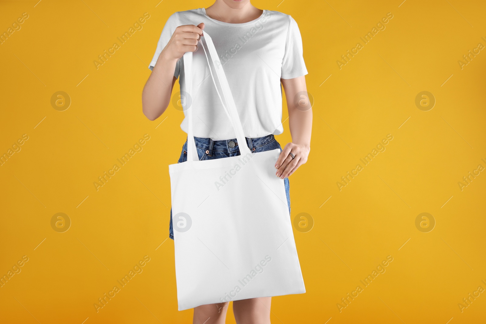 Photo of Woman with white textile bag on orange background, closeup. Space for design