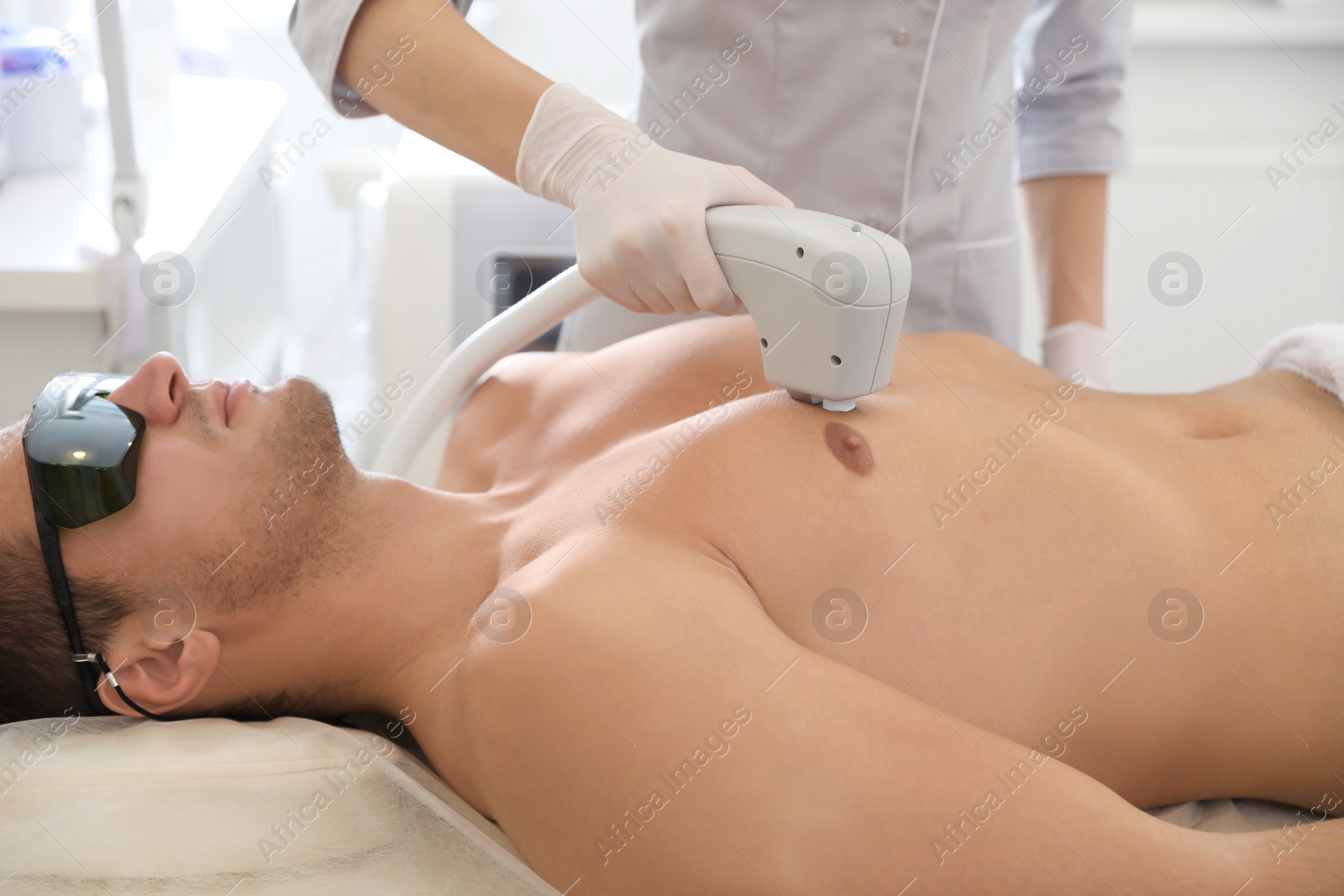 Photo of Young man undergoing laser epilation procedure in beauty salon, closeup
