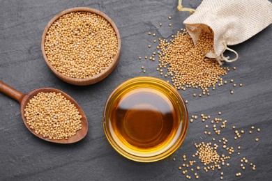 Photo of Bowl with natural oil and mustard seeds on black table, flat lay